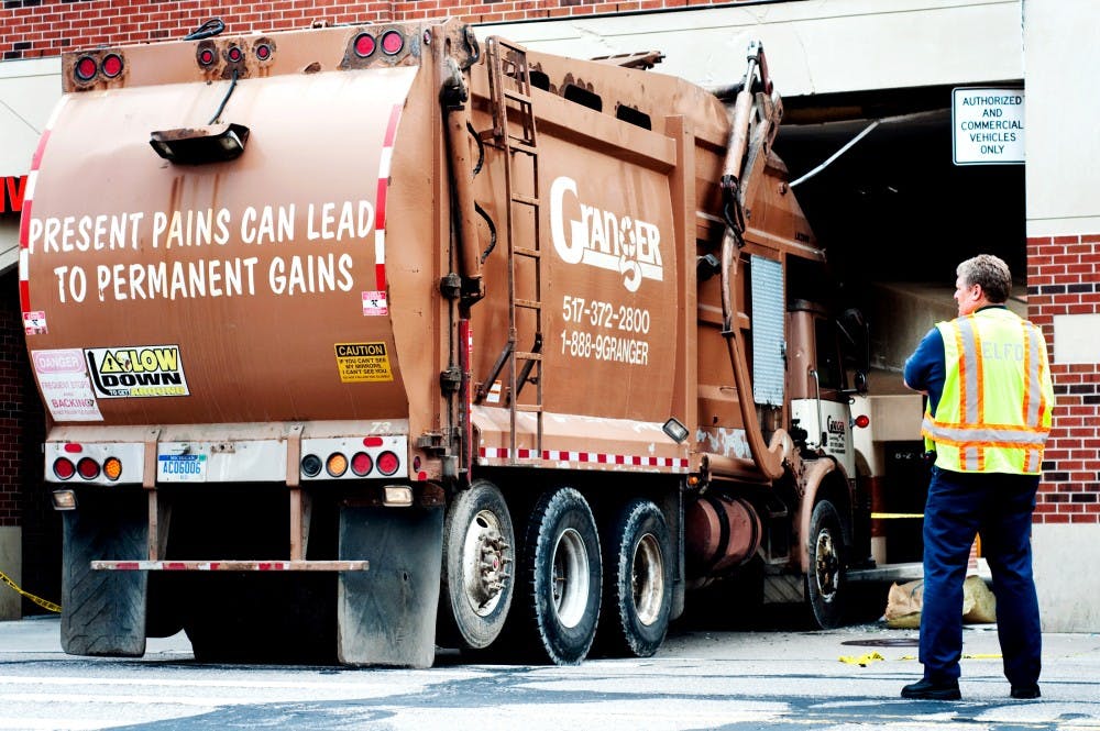 	<p>Lt. Bill Drury of the East Lansing Fire Department watches a Granger garbage truck as it attempts to back out of the sticky situation the driver placed it in. The driver of the truck was taken to Sparrow Hospital after he crashed into the archway of the alley between condominiums on 220 M.A.C. Ave. and <span class="caps">CVS</span> Pharmacy, 240 M.A.C. Ave. </p>