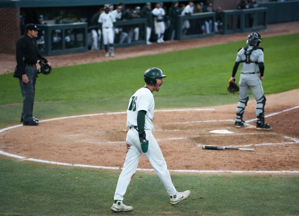 Michigan State redshirt senior outfielder Peter Ahn (16) appears to cheer after scoring a run for the Spartans and seeing that sophomore infielder Brock Vradenburg (28) is safe on first, in the bottom of the fifth. Michigan State won 7-4 against Purdue Fort Wayne at the McLane Stadium, on Apr. 27, 2022.