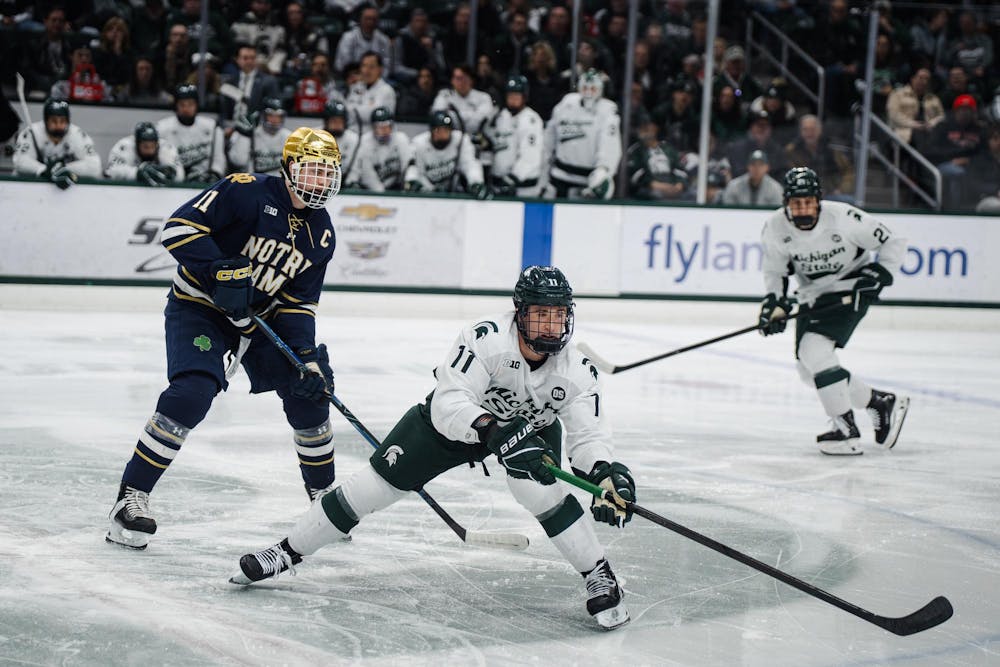 Notre Dame junior Danny Nelson (11), Michigan State sophomore Owen West (11) and Michigan State freshman Anthony Romani (21) reaching for the puck during a game at Munn Ice Arena in East Lansing, Michigan, on Friday, Feb. 20, 2026.