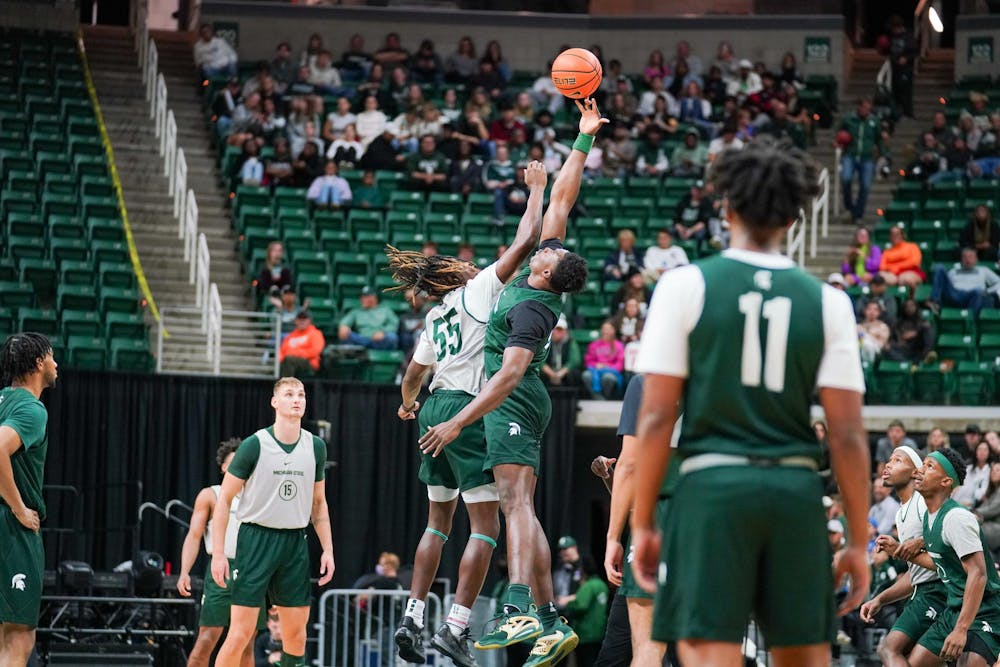 <p>Freshman forward Coen Carr (55) and senior center Mady Sissoko (22) jumping to tip the ball at the start of a scrimmage game during the Michigan State Madness event at the Breslin Center on Oct. 13, 2023.</p>