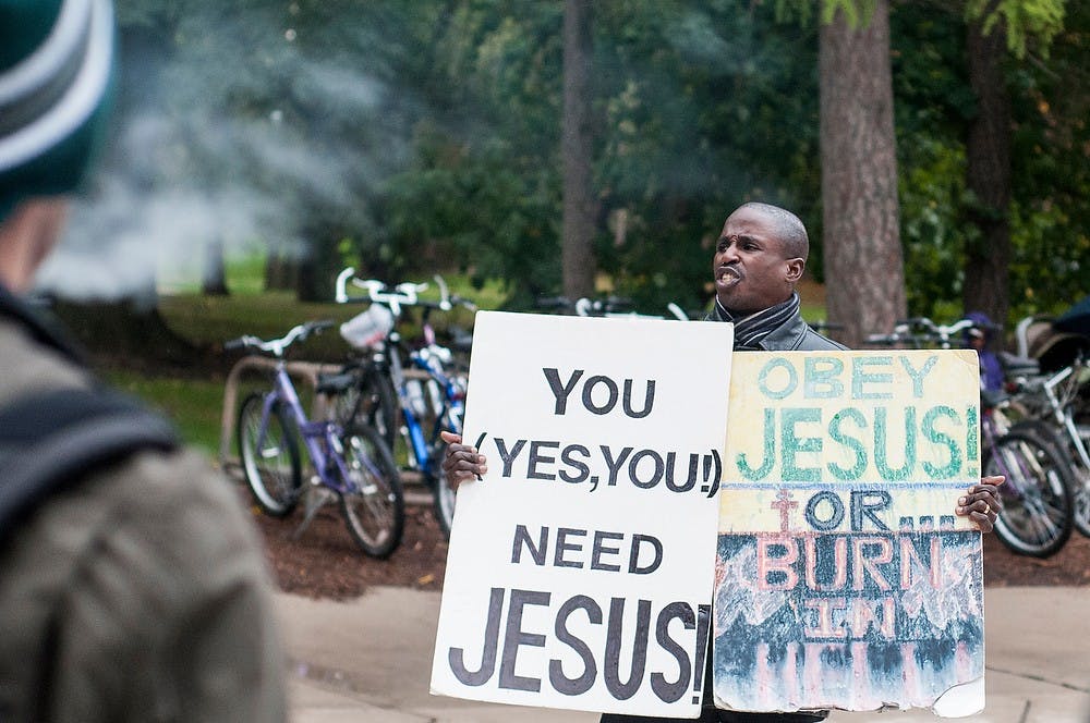 	<p>Wells Hall preacher and <span class="caps">MSU</span> alumnus Michael Venyah calls out a group of students smoking on Oct. 21, 2013, outside Wells Hall. Venyah encourages all students to find Jesus in their lives. Khoa Nguyen/The State News</p>