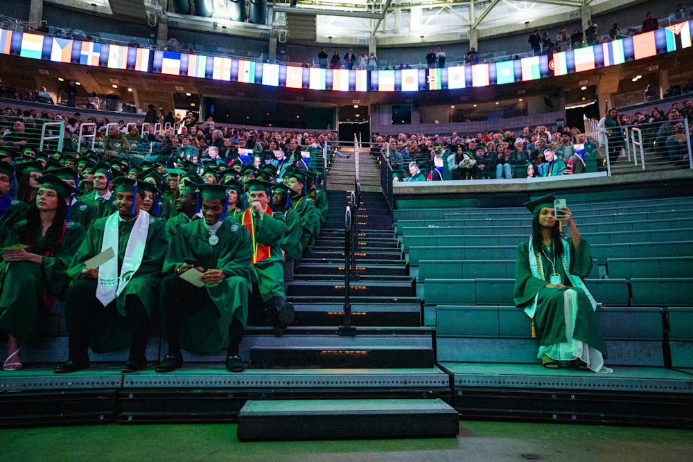 An MSU alumnus records with her phone while Communication Arts & Sciences graduates wait to receive their diplomas during the fall 2024 commencement ceremony at the Breslin Center on Dec. 14, 2024.