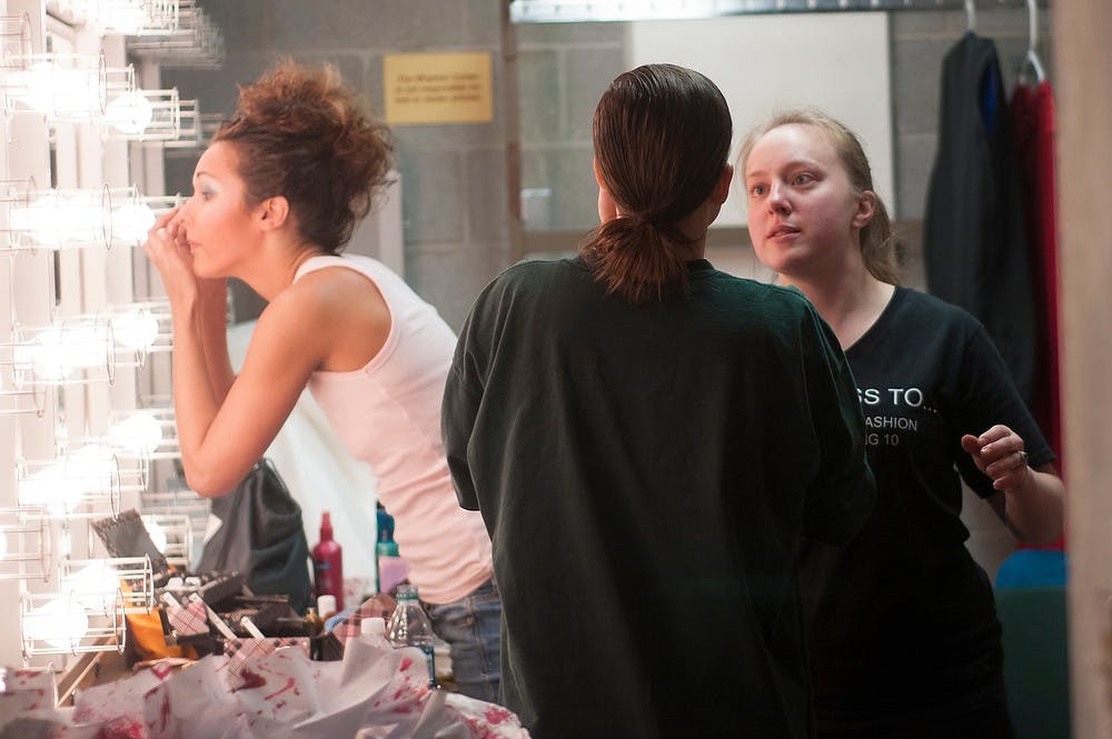 <p>Rochester, Mich. resident Jordan Nelson does her makeup while apparel and textile design junior Katie Raynard puts makeup on environmental and plant biology junior Emily Ward on March 15, 2014, at Wharton Center for Performing Arts. Raynard did the girls' hair and makeup for the Apparel and Textile Design Fashion Show. Betsy Agosta/The State News</p>