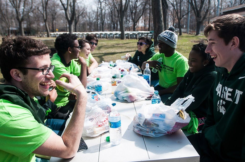 <p>Biochemistry senior Driton Gacaferi, left, and human biology freshman Billy Comstock enjoy their lunch with the other volunteers April 12, 2014, during MSU's Global Day of Service at Patriarche Park. MSU students did acts of service in several locations in East Lansing and Lansing. Erin Hampton/The State News</p>