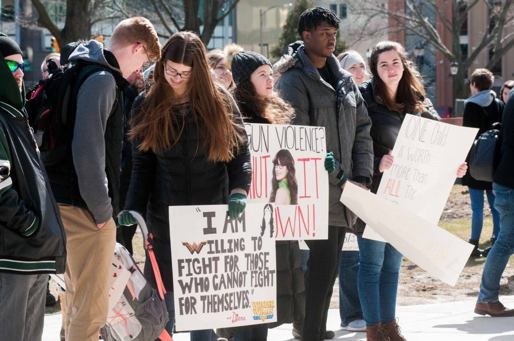 <p>Political science and pre-law junior Daniel Lock, far left, business and political science and pre-law sophomore Sydney Darnall, secondary education sophomore Kelly Hansen, secondary education sophomore Emanuel Williams, and elementary education sophomore Mallory Weiner, far right, hold signs at the Students Demand Action Rally on March 14, 2018 at the Michigan State Capitol. (Annie Barker | State News)</p>