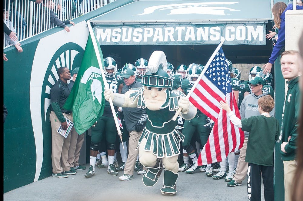 <p>Sparty and the MSU football team run on the field prior to the Green and White Spring Game on April 25, 2015, at Spartan Stadium. The white team defeated the green team, 9-3.</p>