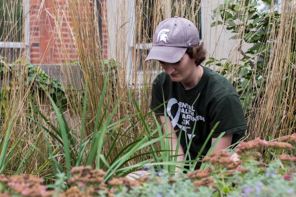 Doctoral candidate of biosystems engineering Kaitlyn Casulli plants irises outside of Olin Health Center on Oct. 10, 2018. Casulli was one of the organizers of the event.