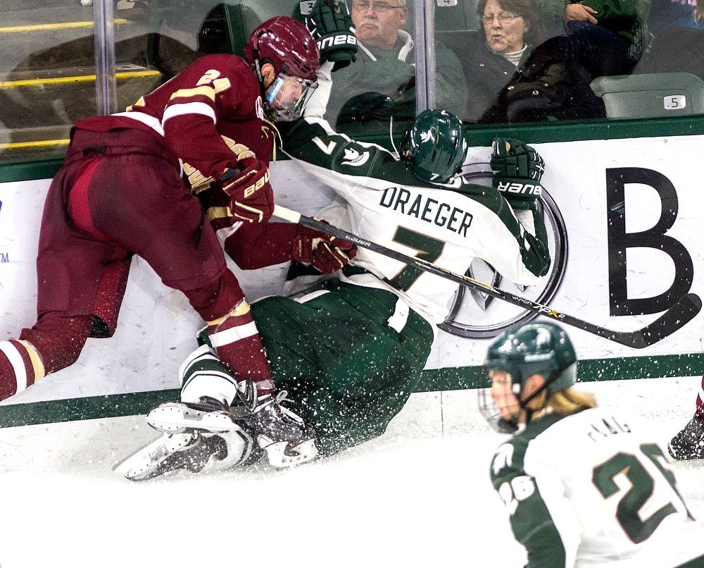 <p>Junior defender John Draeger falls after he collides into Boston College forward Zach Sanford Nov. 14, 2014, during the game at Munn Ice Arena. The Spartans lost to the Eagles, 3-2. Erin hampton/The State News</p>