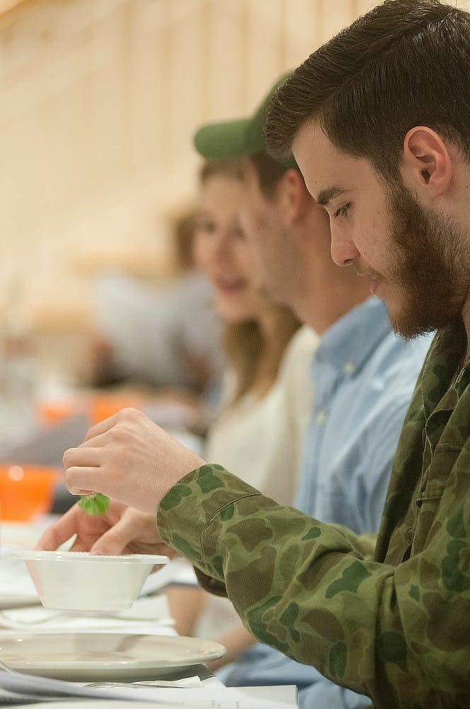 <p>Political theory and constitutional democracy sophomore Blake Isaacs dips parsley in salt water during a Passover meal April 3, 2015, at the Lester and Jewell Morris Hillel Jewish Student Center, 360 Charles St. in East Lansing. Passover is a traditional celebration that commemorates Jewish freedom from slavery in Egypt. Alice Kole/The State News </p>