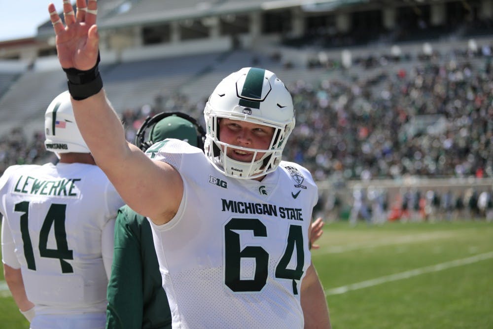 Senior center Matt Allen (64) waves to the crowd before the start of the Green and White game at the Spartan Stadium on April 13, 2019.