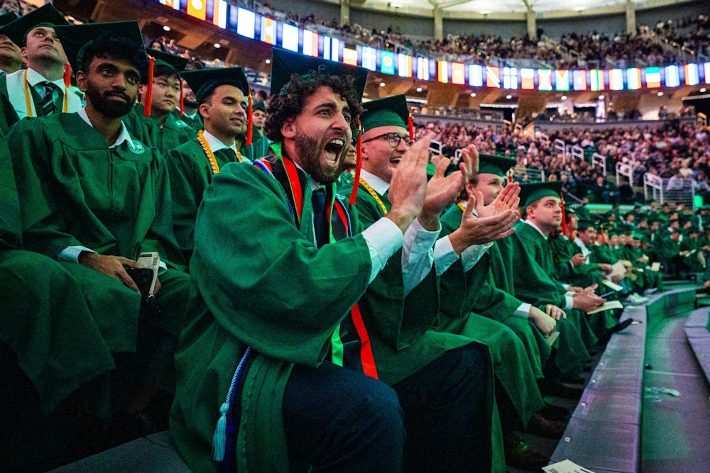 MSU alumni cheer on their friend as they receive their diploma during the fall 2024 commencement ceremony at the Breslin Center on Dec. 14, 2024.