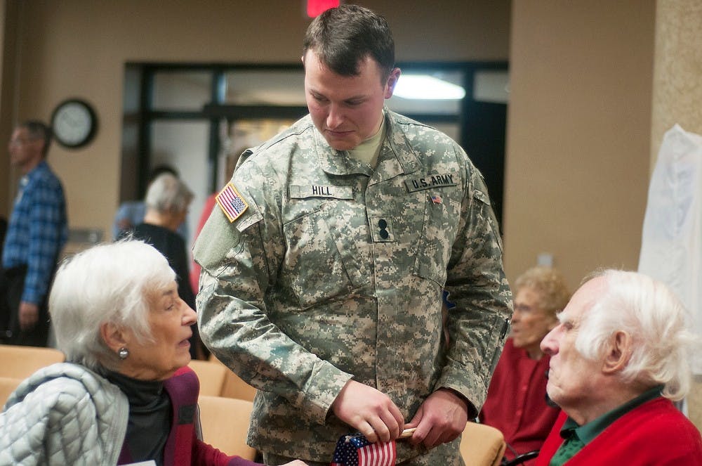 	<p>Communication and psychology senior Eric Hill speaks with Okemos resident Carol Beecher and East Lansing resident William Beecher during a Veterans Day ceremony Nov. 11, 2013, at Burcham Hills Retirement Community, 2700 Burcham Dr. Cadets and veterans were given American flag pins and certificates during a ceremony thanking them for their service. Danyelle Morrow/The State News</p>