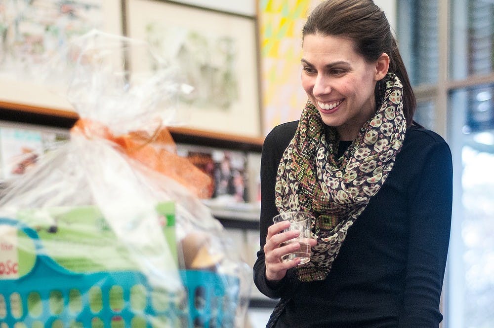 	<p>East Lansing resident Ann Lawrie smiles while browsing the variety of items available for the silent auction during the Books, Bites, and Bids fundraiser April 19, 2013, at the East Lansing Public Library, 950 Abbot Road. The event was a special conclusion to National Library Week. </p>