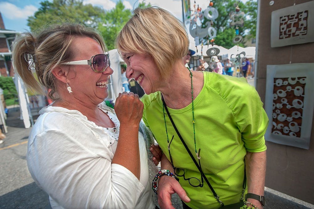 	<p>Holland, Mich. resident Laura Lurin, left, shares a moment with her sister East Lansing resident Linda Grua as they were shopping for art on May 19, 2013, at the East Lansing Art Festival. This was the 50th anniversary of the festival, with 170 artists participating in the two-day event. Justin Wan/The State News</p>