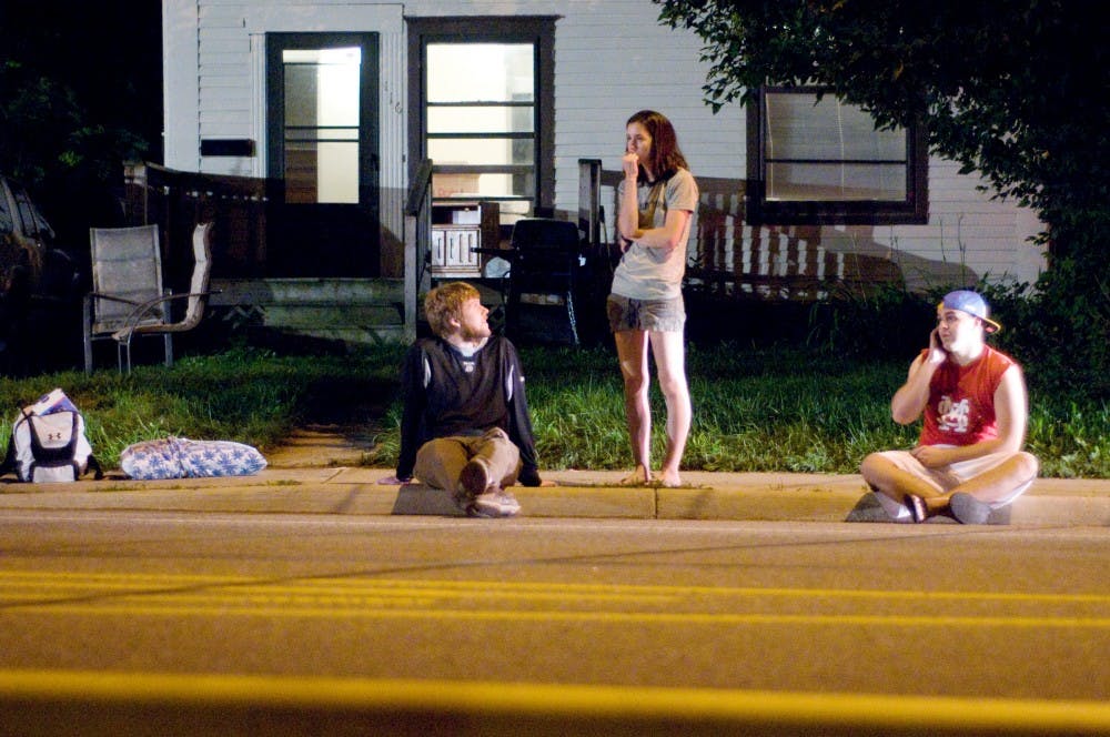 <p>From left, psychology senior Jonathan Bomar, East Lansing resident Sarah Kwiatkowski and journalism senior Steven Miller wait on the curb as East Lansing and Meridian Township firefighters extinguish and investigate a fire that erupted in their apartment building, 129 Burcham Apartments, late Monday night. All residents were evacuated and unharmed.</p>