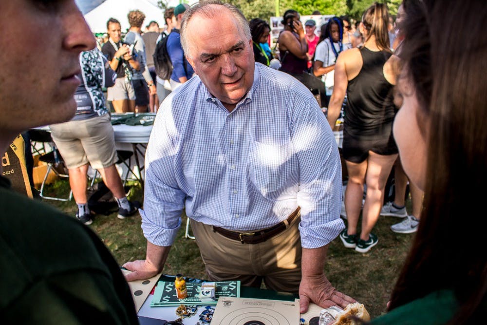 <p>Interim MSU president John Engler listens to students talk during Sparticipation Aug. 28, 2018 at Cherry Lane Field. Thousands of students attended the annual event which gives student organizations the chance to recruit new members.</p>