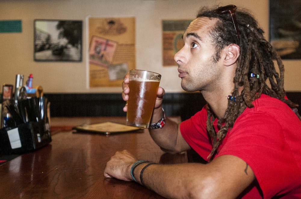 Lansing resident Joshua Burt enjoys a cold beer at Woody's Oasis Bar & Grill located at 211 East Grand River Avenue.  The Woody's at 1050 Trowbridge Road has applied for their liquor license to start serving alcoholic beverages. Adam Toolin/The State News