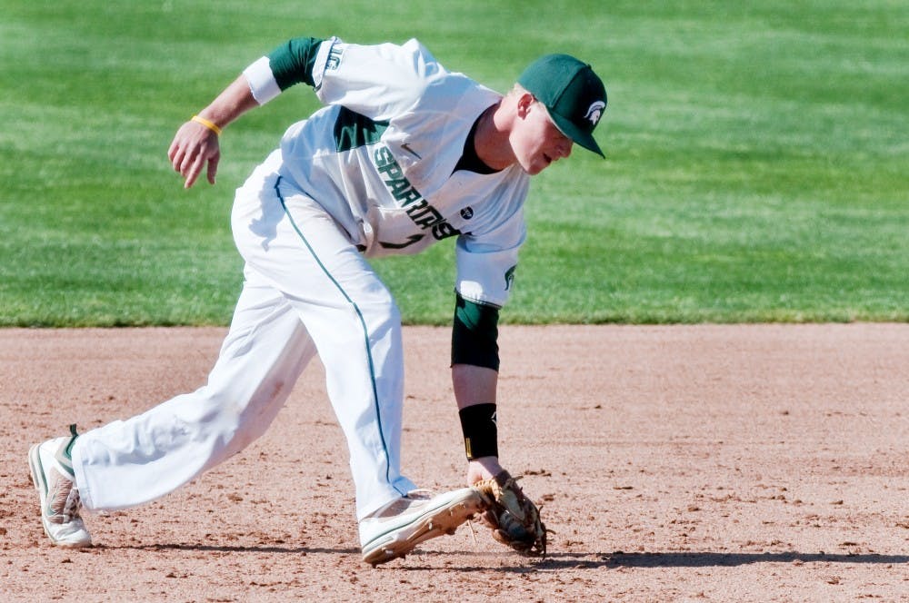 Junior outfielder and infielder Torsten Boss picks up a ball from the field before sending it to the first base to end a Western Michigan hit. The Spartans defeated the Broncos, 13-3, Tuesday afternoon at McLane Baseball Stadium at Old College Field. Justin Wan/The State News