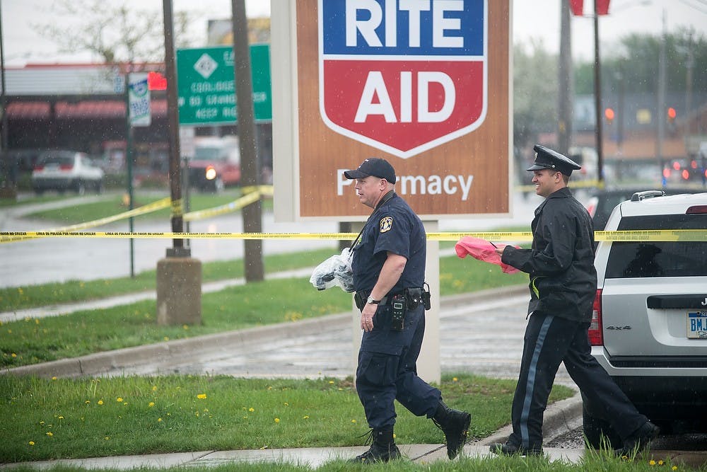 <p>Police investigate a shooting May 12, 2014, at Rite Aid, 3106 E. Saginaw street. The suspect fled on foot after firing shots, killing an employee. Danyelle Morrow/The State News</p>