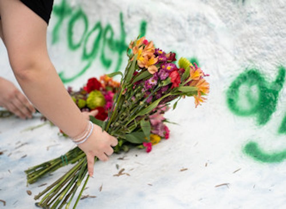 Kelly Branigan and Paige Mulligan lay flowers at the base of The Rock on Farm Lane on May 10, 2022 for the recently deceased Adreian Payne.