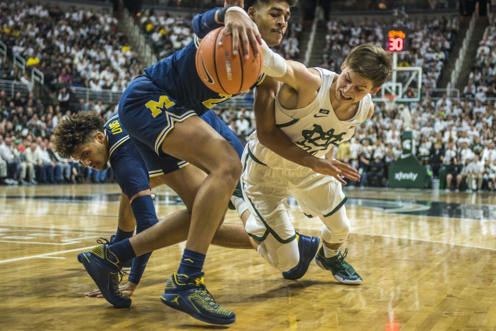 Junior guard Matt McQuaid (20) dives for the ball during the first half of the men's basketball game against Michigan on Jan. 13, 2018 at Breslin Center. The Spartan's led the first half, 37-34. (Nic Antaya | The State News)