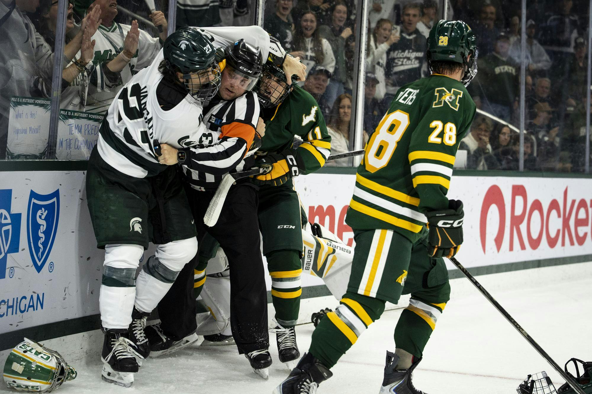 <p>Michigan State junior forward Shane Vansaghi (23) wrestles with a referee and Northern Michigan junior forward Brendan Lamb (11) during a scrum at Munn Ice Arena in East Lansing, Mich., on Friday, Oct. 9, 2026.</p>