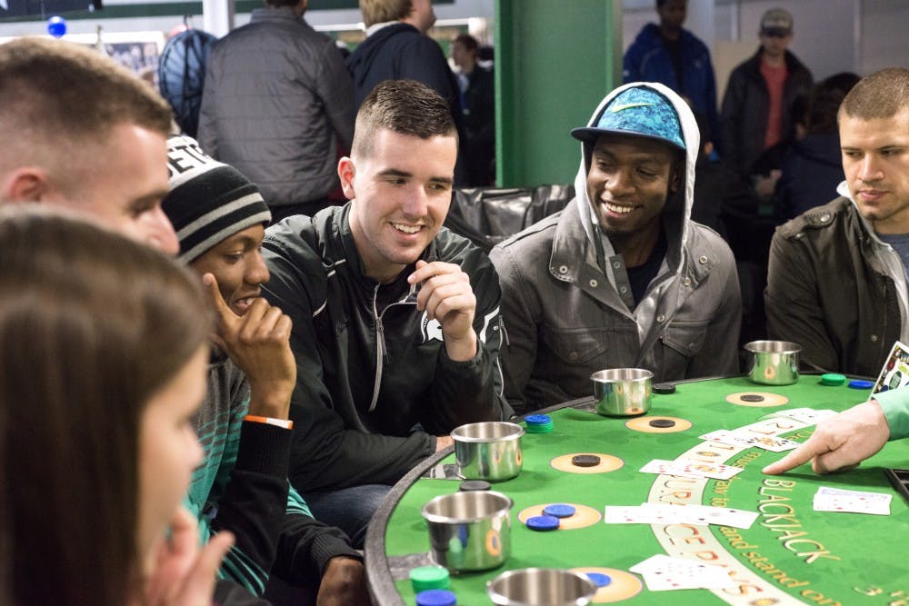 From left to right, kinesiology senior Alexander Woods, applied engineering junior Matt Mueller, actuarial science senior Marcus Oden, and zoology senior John Kochiss engage in a game of blackjack during MSU Ice and Dice on Feb. 27, 2016 at Munn Ice Arena.