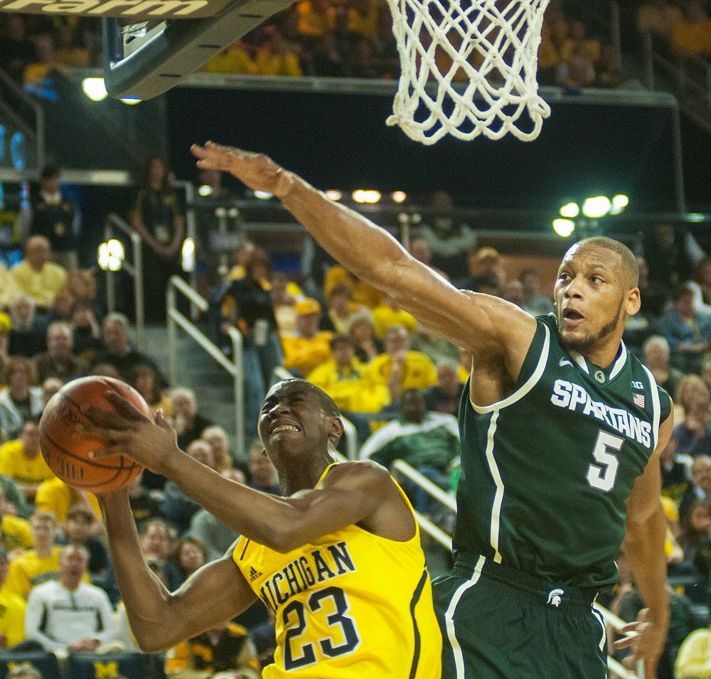 <p>Then-senior center Adreian Payne jumps over Michigan guard Caris Levert to attempt to block a shot Feb. 23,  2014, at Crisler Center in Ann Arbor, Mich. Danyelle Morrow/The State News</p>