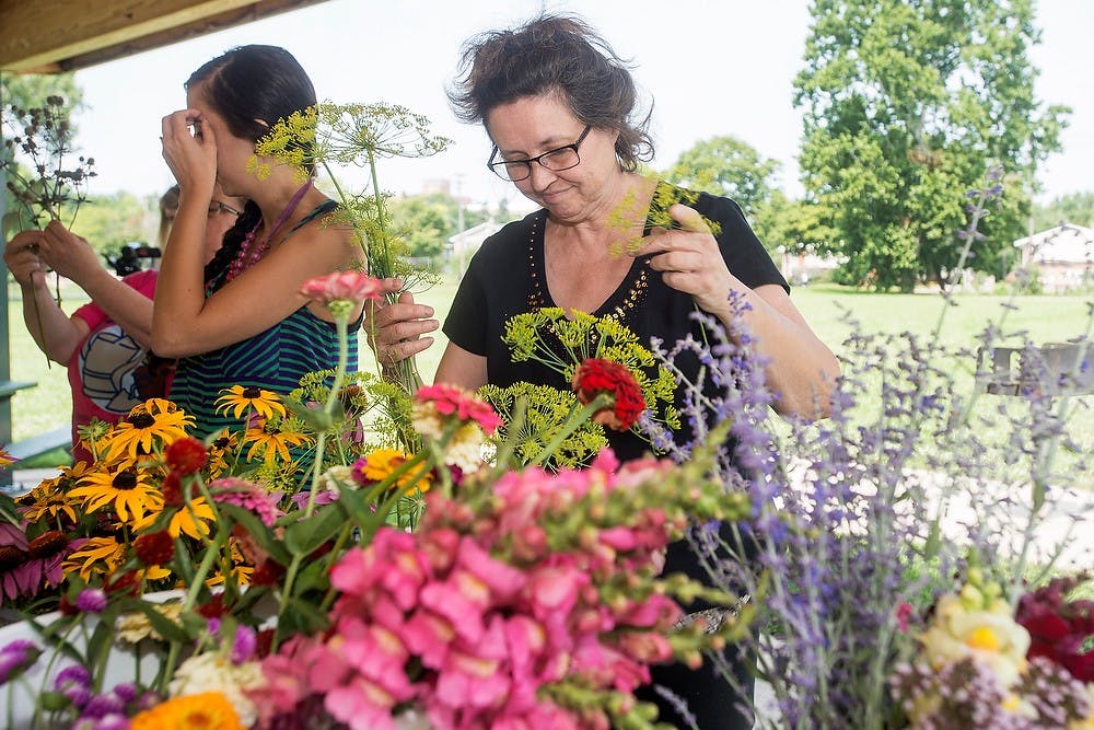 <p>Williamston, Mich., resident Mary Clare Brown picks out flowers for an arrangement during a workshop, Aug. 2, 2014, at the Allen Neighborhood Center's Hunter Park GardenHouse in Lansing. The workshop taught attendees how to best use garden flowers in vases. Danyelle Morrow/The State News</p>