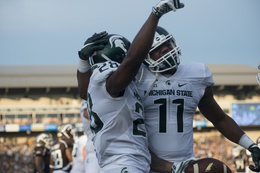 <p>Freshman running back Madre London, left, celebrates his touchdown with junior tight end Jamal Lyles on Sept. 4, 2015, during a game against Western Michigan at Waldo Stadium in Kalamazoo, Mich. The Spartans beat the Broncos, 37-24. Julia Nagy/The State News</p>