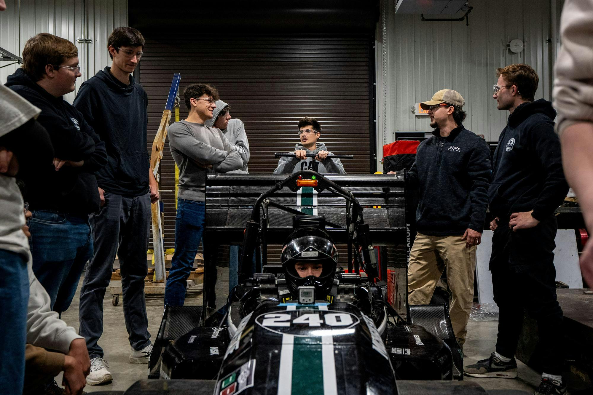 <p>MSU student and member of MSU Formula Racing Team, Carter Ross, sits in car during a center of gravity test as the team discusses the next trial at Michigan State University's William A. Demmer Engineeing Center in East Lansing, Mich, on Saturday, Nov. 8, 2025.</p>