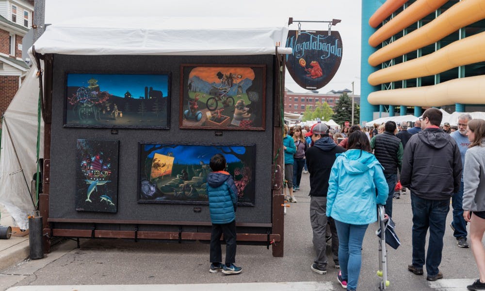 A young boy looks at art by Andy Van Schyndle during the East Lansing Art Festival on May 18, 2019.