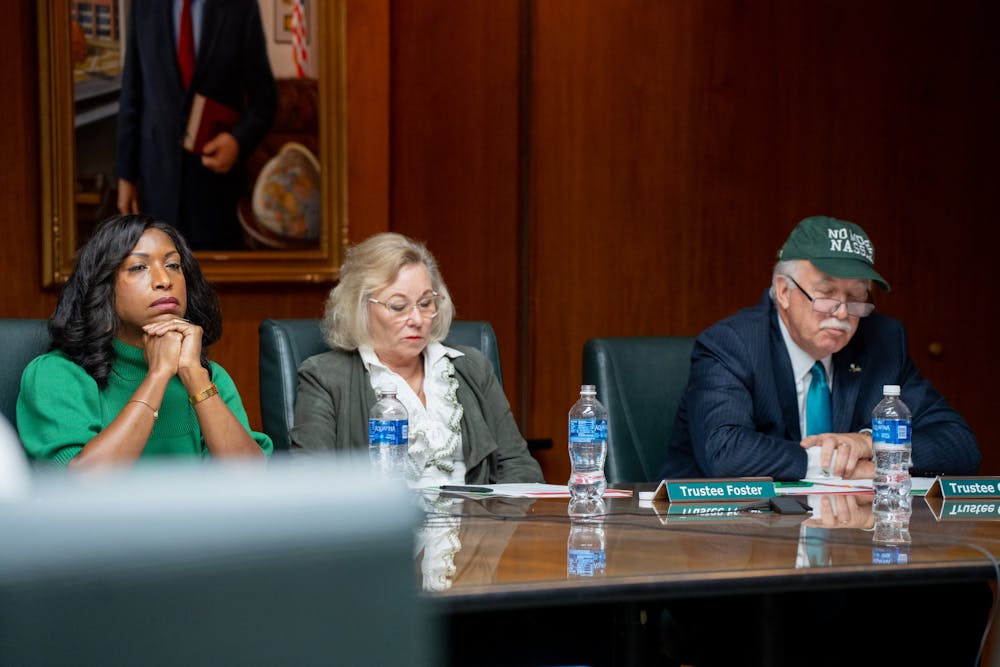 Michigan State University Trustees Brianna T. Scott and Melanie Foster listen as Trustee Pat O'Keefe delivers remarks, in which he put on a "No More Nassar" hat to prove one of his points at the Board of Trustees meeting on Oct. 28, 2022.