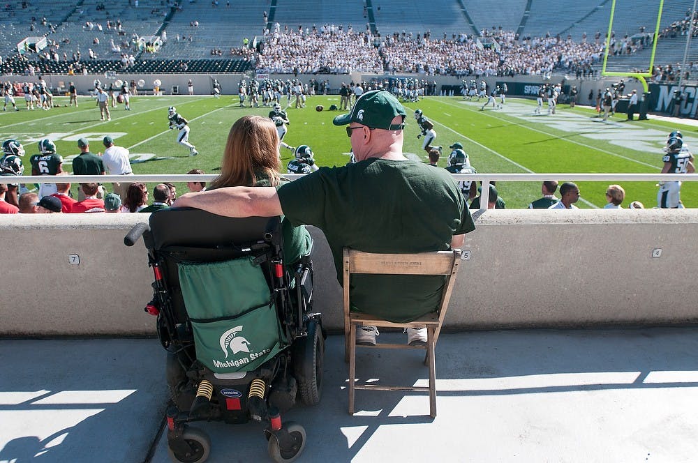 <p>Advertising junior Katie Feirer watches the Spartans warm up with her step-father Daniel Heyden in a handicap seating section before the game against Wyoming on Sept. 27, 2014, at Spartan Stadium. Her seats were across from the student section. Feirer said she feels segregated from the student body during the games because she is unable to sit in the student section. Julia Nagy/The State News</p>