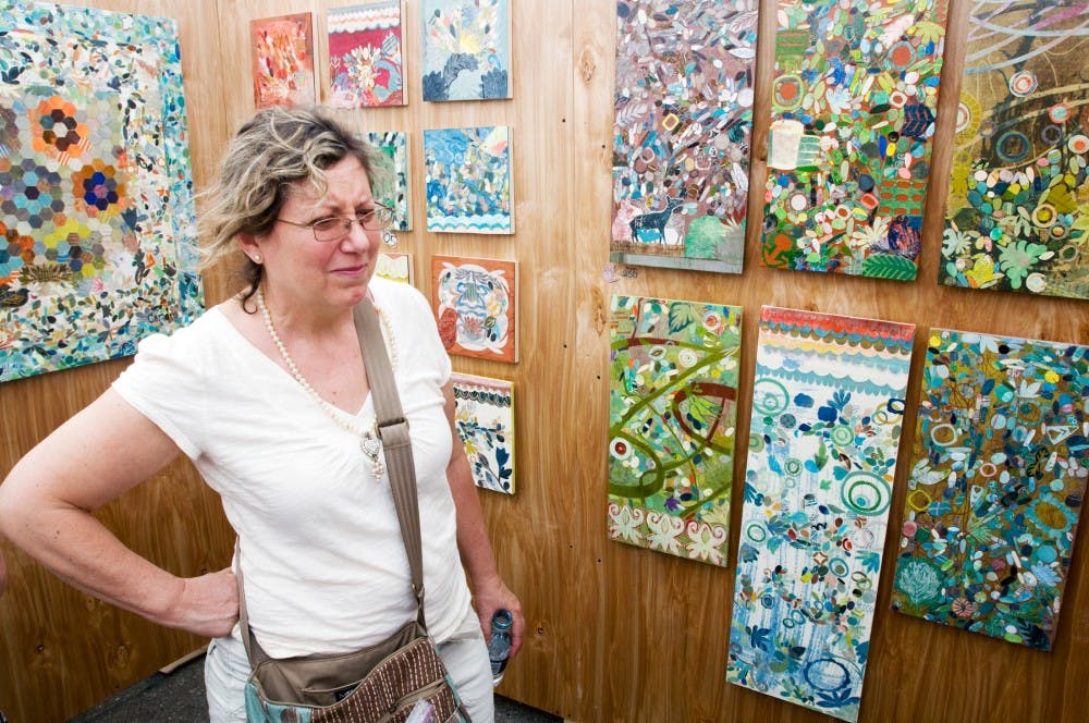 	<p>Okemos resident Cathy Harris admires the work of artist Sandra Boggs Sunday afternoon at the 48th Annual East Lansing Art Festival. Boggs takes her own mono prints that she doesn&#8217;t like and cuts them up to form the collages that are her artwork.</p>