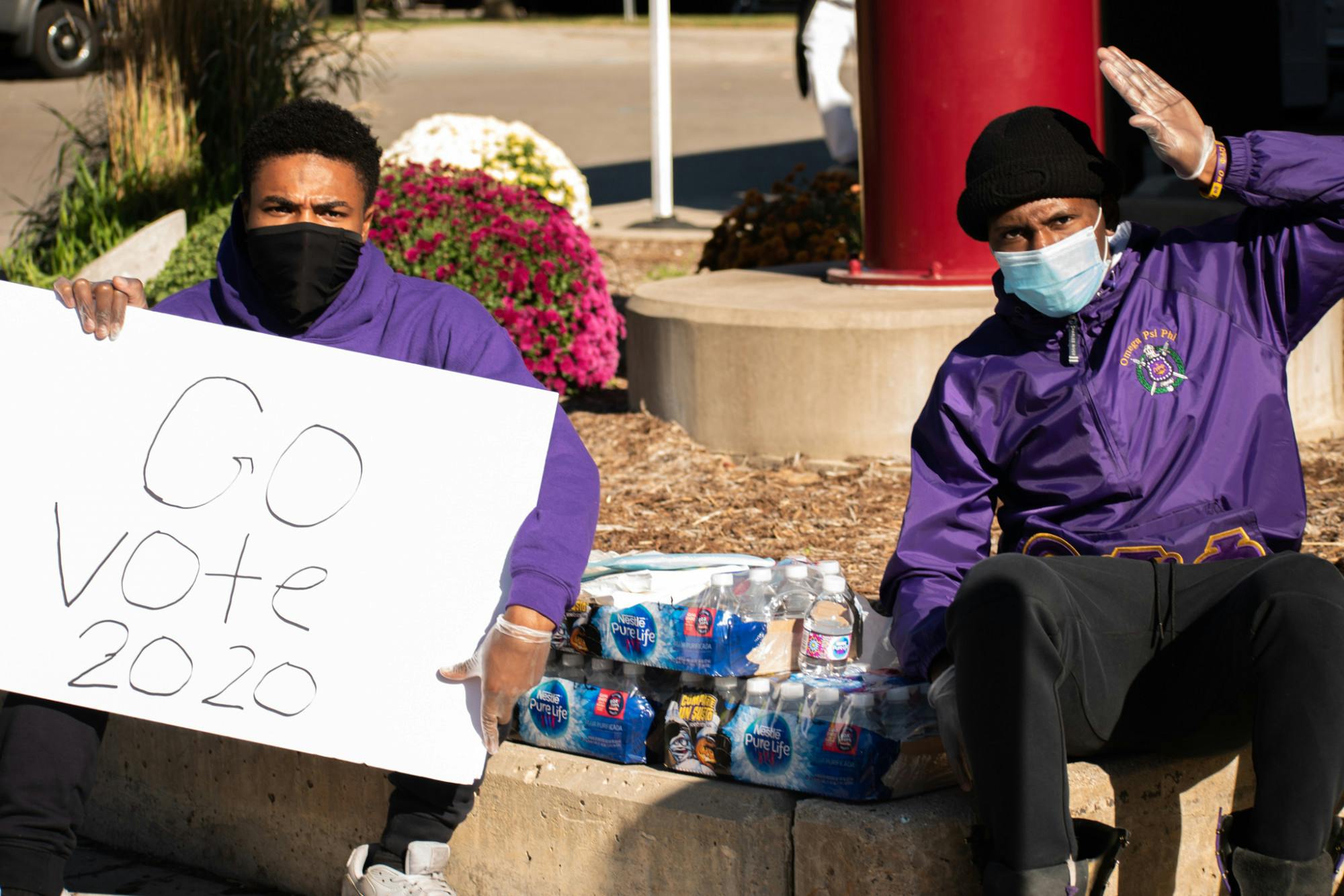 <p>Anthony Hines Jr. (left) and Ryan Thomas (right) of MSU&#x27;s Omega Psi Phi hand out water bottles to voters in front of the East Lansing clerk&#x27;s office during Election Day 2020. In a message directed toward students who hadn&#x27;t voted yet, Hines Jr. firmly said, &quot;Vote, simple.&quot; </p>