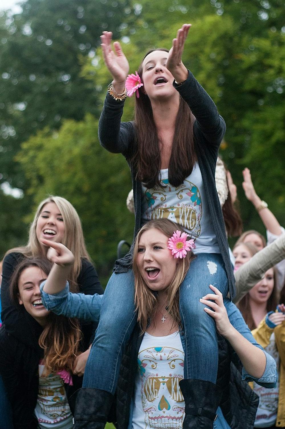 <p>Elementary education senior Alexandria Warren sits on comparative cultures and politics senior Abigail Barwig's shoulders during bid day on Sept. 15, 2014, at the Rock on Farm Lane. All of the sororities joined at the Rock to greet their new members. Jessalyn Tamez/The State News </p>