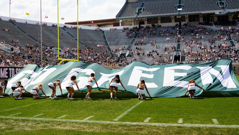 Michigan State University cheerleaders open a banner reading "GO GREEN" duringthe  MSU football spring open practice, held at Spartan Stadium on April 15, 2023.