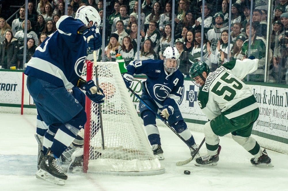 Junior center Patrick Khodorenko (55) fights for the puck during the game against Penn State at Munn Ice Arena on Feb. 15, 2019. The Spartans lead the Nittany Lions 2-1 after the first period.