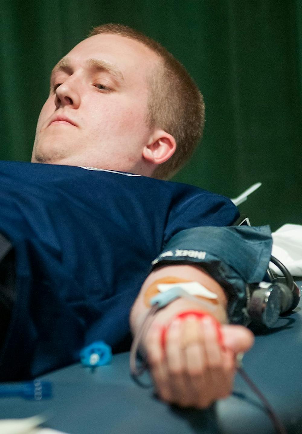 	<p>Chemistry senior John Kanitra lays down while he is donating blood, June 26, 2013, inside Communication Arts and Sciences Building. Blood donors could vote for police or fire department in the Battle for Blood challenge. Justin Wan/The State News</p>