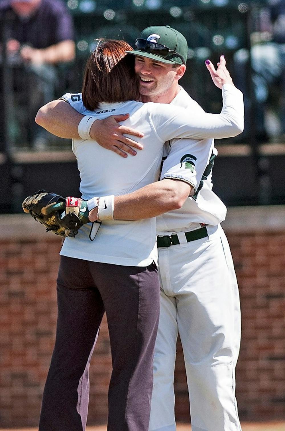 <p>Volleyball head coach Cathy George hugs first baseman Ryan Krill on April 9, 2014, before a baseball game against Western at McLane Stadium at Old College Field. George was throwing the ceremonial first pitch. Erin Hampton/The State News</p>