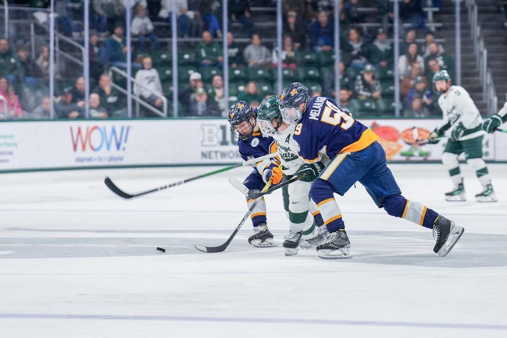 <p>Two Canisius players on either side of a Michigan State player during a game between each other at Munn Ice Arena on Oct. 19, 2023. The Spartans beat the Griffins 6-3 in one of a two-game series.</p>