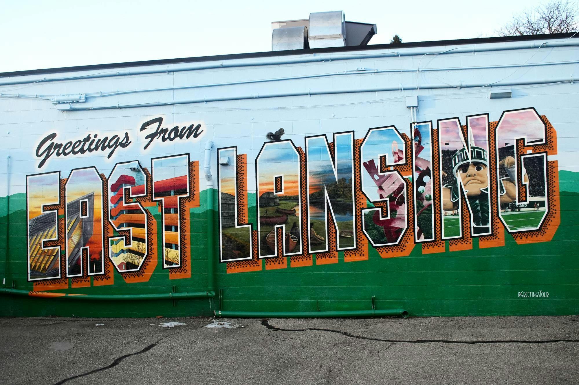 <p>The "Greetings from East Lansing" mural is painted on North Harrison Road placed behind Roadhouse Pub. This was painted by @greetingtours in 2021.</p>