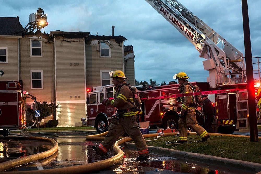 <p>Firemen work to put out a fire Oct. 5, 2014, at The Landings at Chandler Crossings. Erin Hampton/The State News</p>
