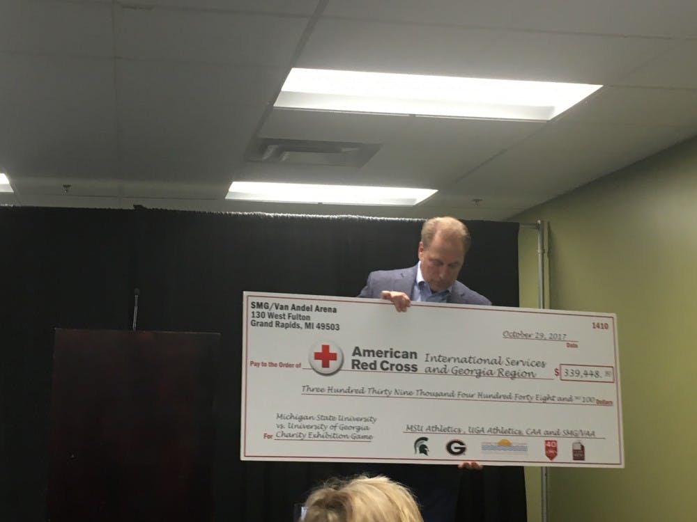 Tom Izzo holds the check being given to the Red Cross following the men's basketball's exhibition game against Georgia.