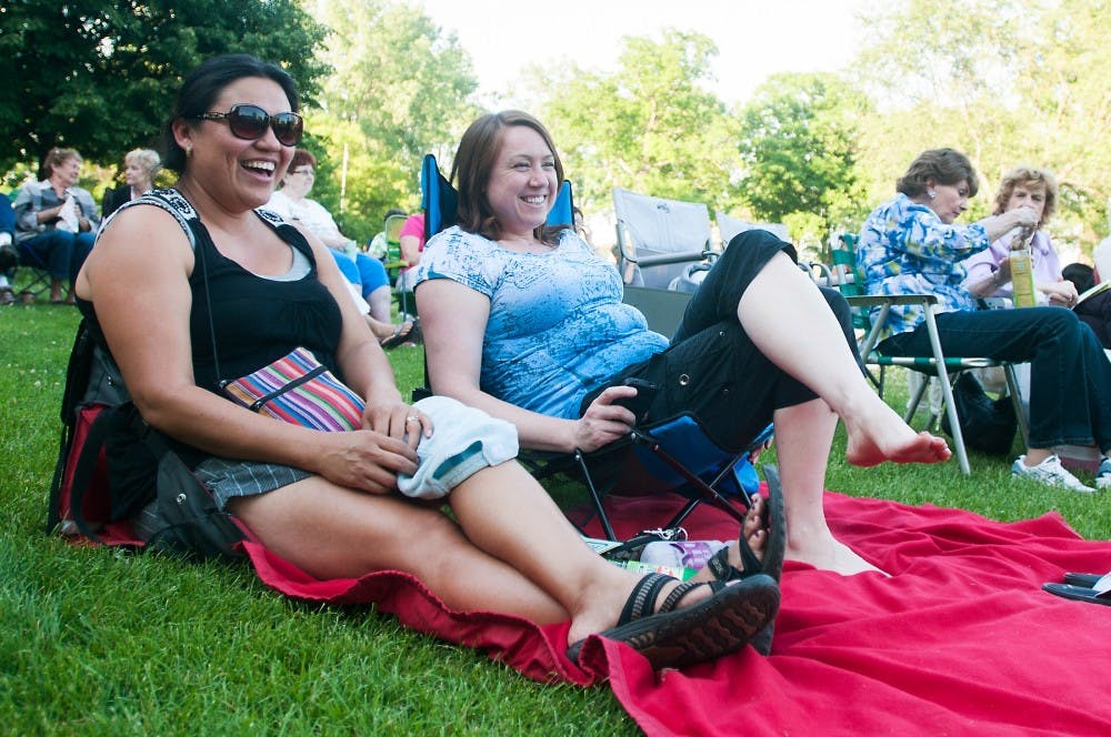 Haslett, Mich., residents Iris Freridge, left, and Miranda Cristales laugh together on June 6, 2014 at Lake Lansing Park South in Meridian Charter Township, Mich. The Lansing based musical group Soulstice performed the opening night of the summer concert series.  