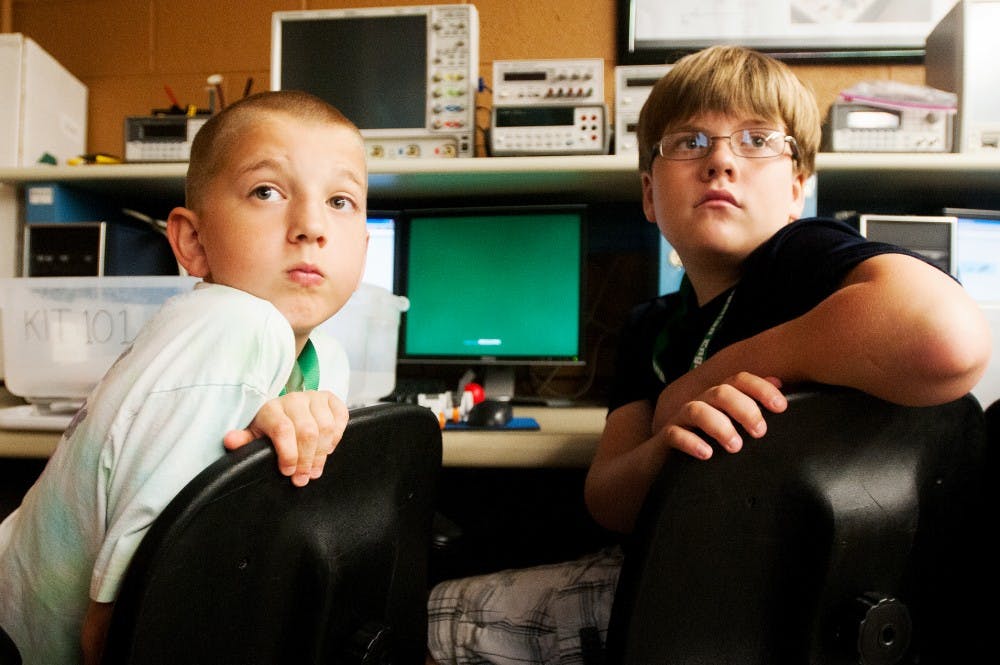 From right, Haslett resident Ryan Stevenson, 11, and Okemos resident Jack Behan, 10, listen to K-12 Outreach Coordinator Bob Watson speak during at Spartaneering, a Lego robotics class, on Monday morning in the Engineering Building. The class is presented by the College of Engineering. Samantha Radecki/The State News
