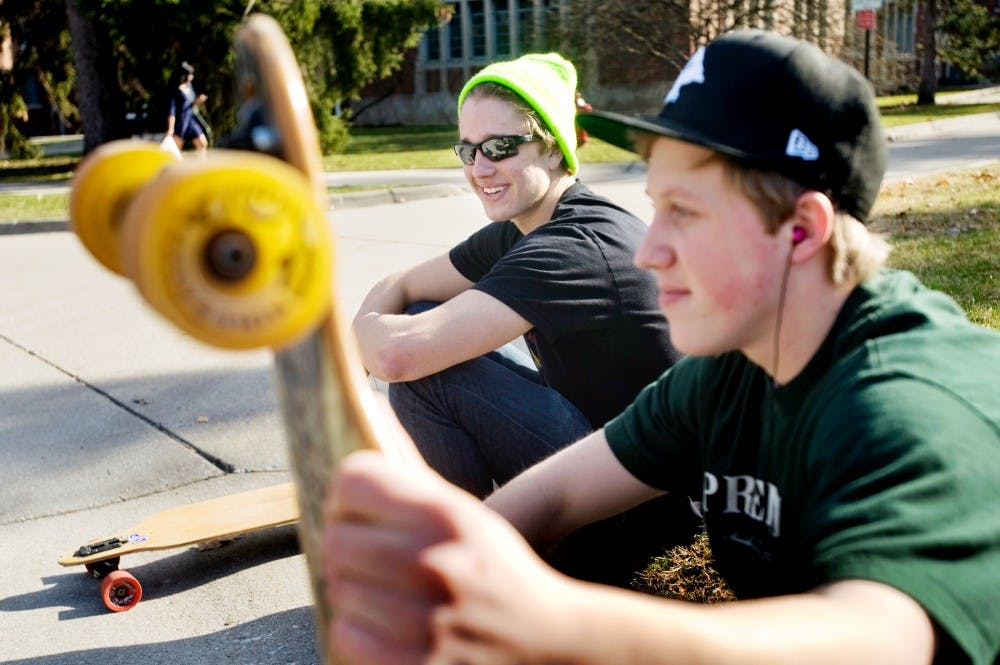 Psychology freshman Alex Schrotenboer, left, smiles as he takes a rest outside Gilchrist Hall Tuesday afternoon after longboarding with Matt Smith, freshman in turfgrass management program. The weather in East Lansing hit a high of 64 degree on Tuesday, and the temperature is projected to be 25 to 30 degrees higher than average of March. Justin Wan/The State News