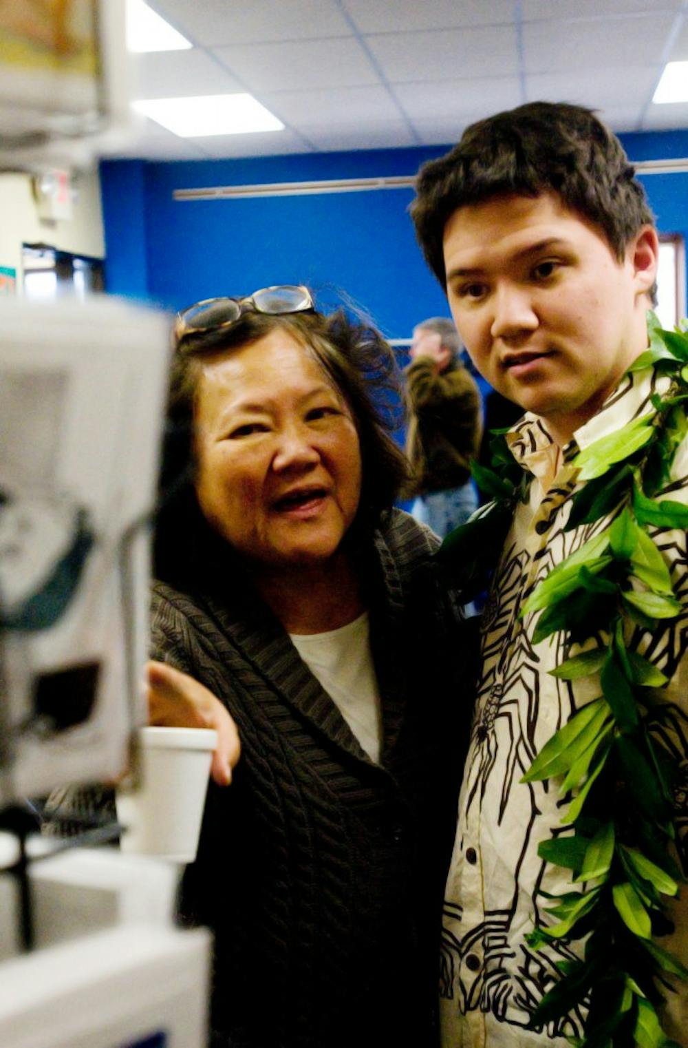 Esther Onaga, associate professor in the department of human development and family studies, and her son, Scott Fergus, look at Fergus' work on display at the Capital Area District Library in Okemos on Sunday afternoon. Fergus' exhibit will be on display at the library until February 24.  Jaclyn McNeal/The State News