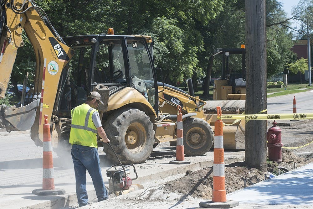 <p>A construction worker makes repairs to Abbot Road in East Lansing on July 27, 2015. Catherine Ferland/ The State News</p>